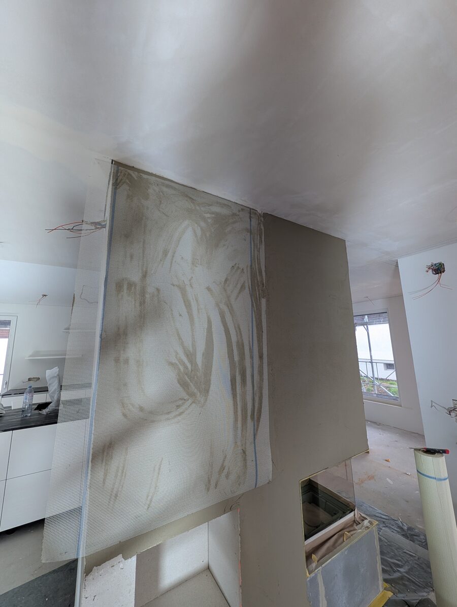 Frisch verputzte Cheminée-Verkleidung mit noch feuchter Putzoberfläche, Blick zur Decke