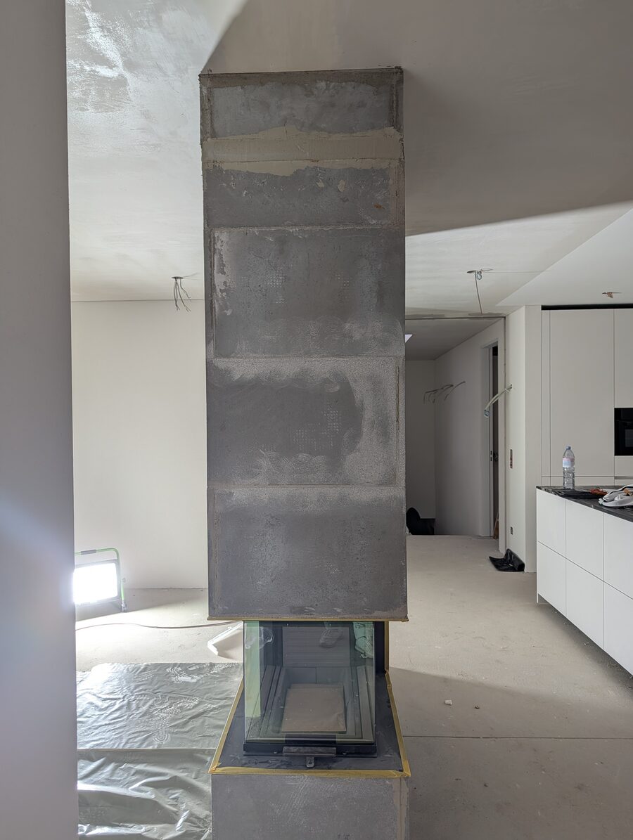 Plattenverkleidung des Cheminées, dahinter die Küchenzeile im Neubau