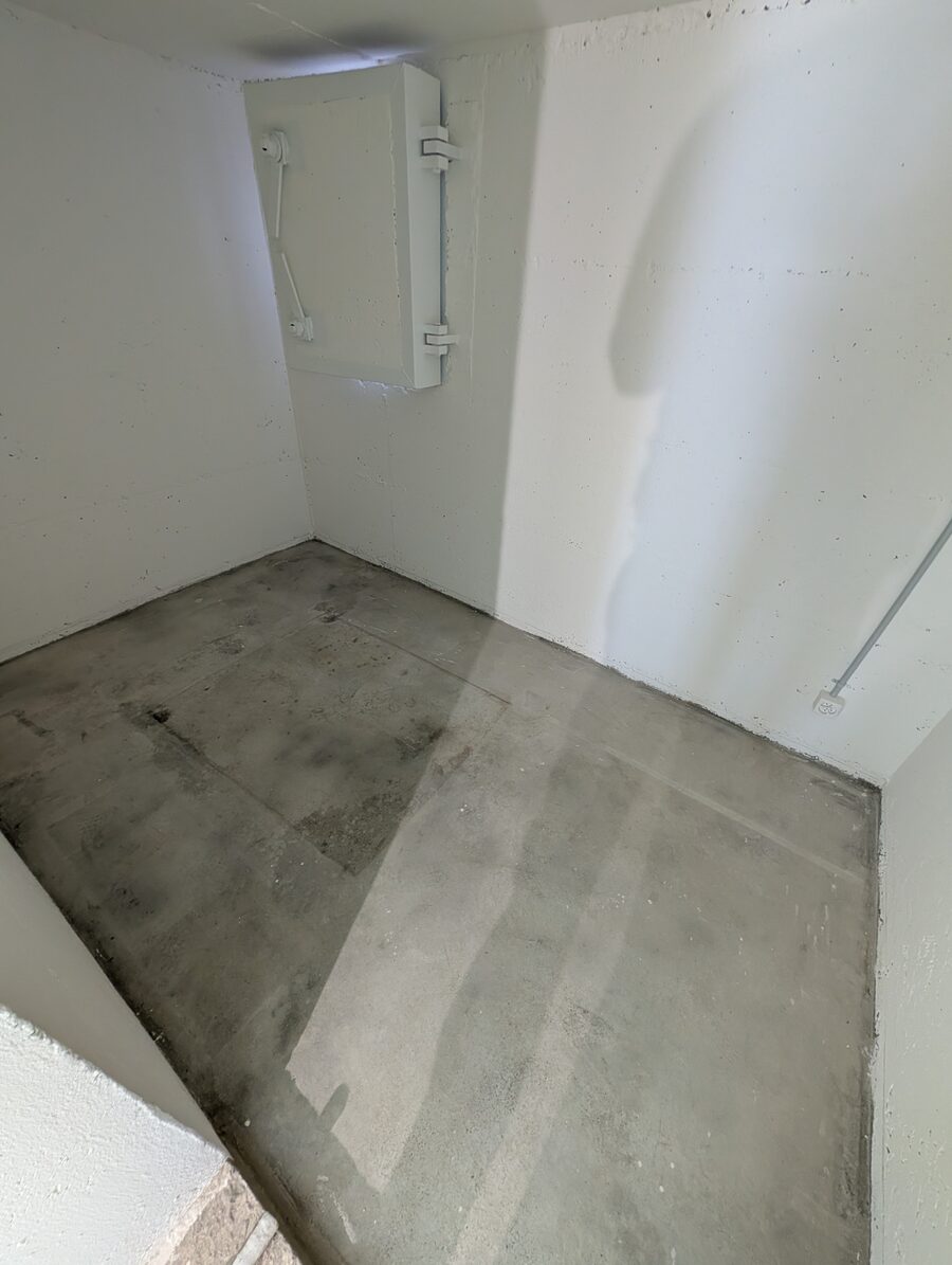 Kellerraum mit rohem Betonboden und weissen Wänden