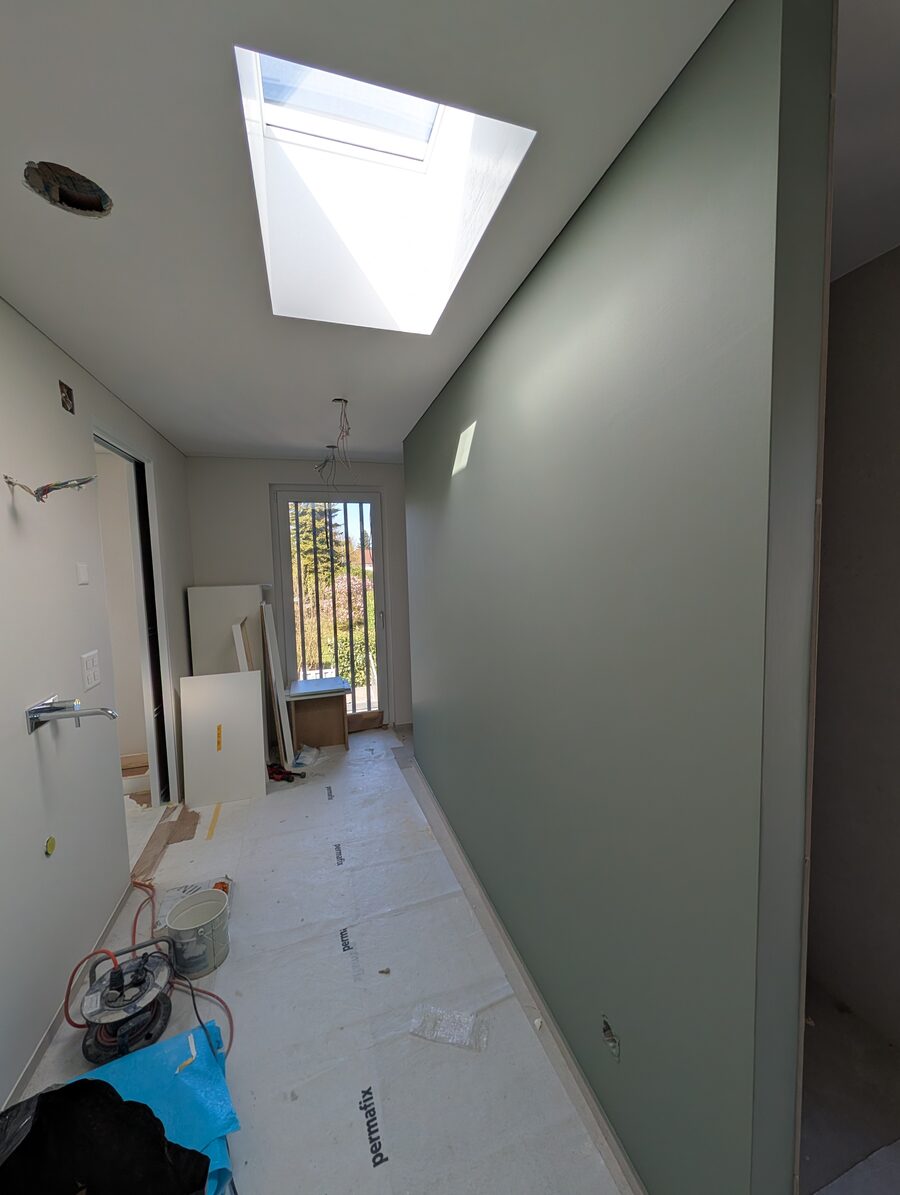Korridor mit salbeigrüner Wand, Oberlicht und Fenster am Ende