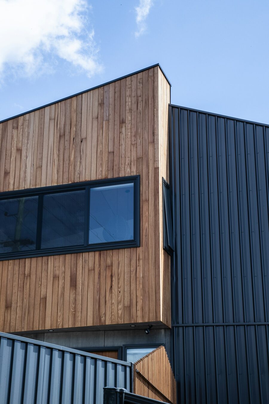 Wohnhaus mit horizontaler Holzfassade und dunklem Anbau